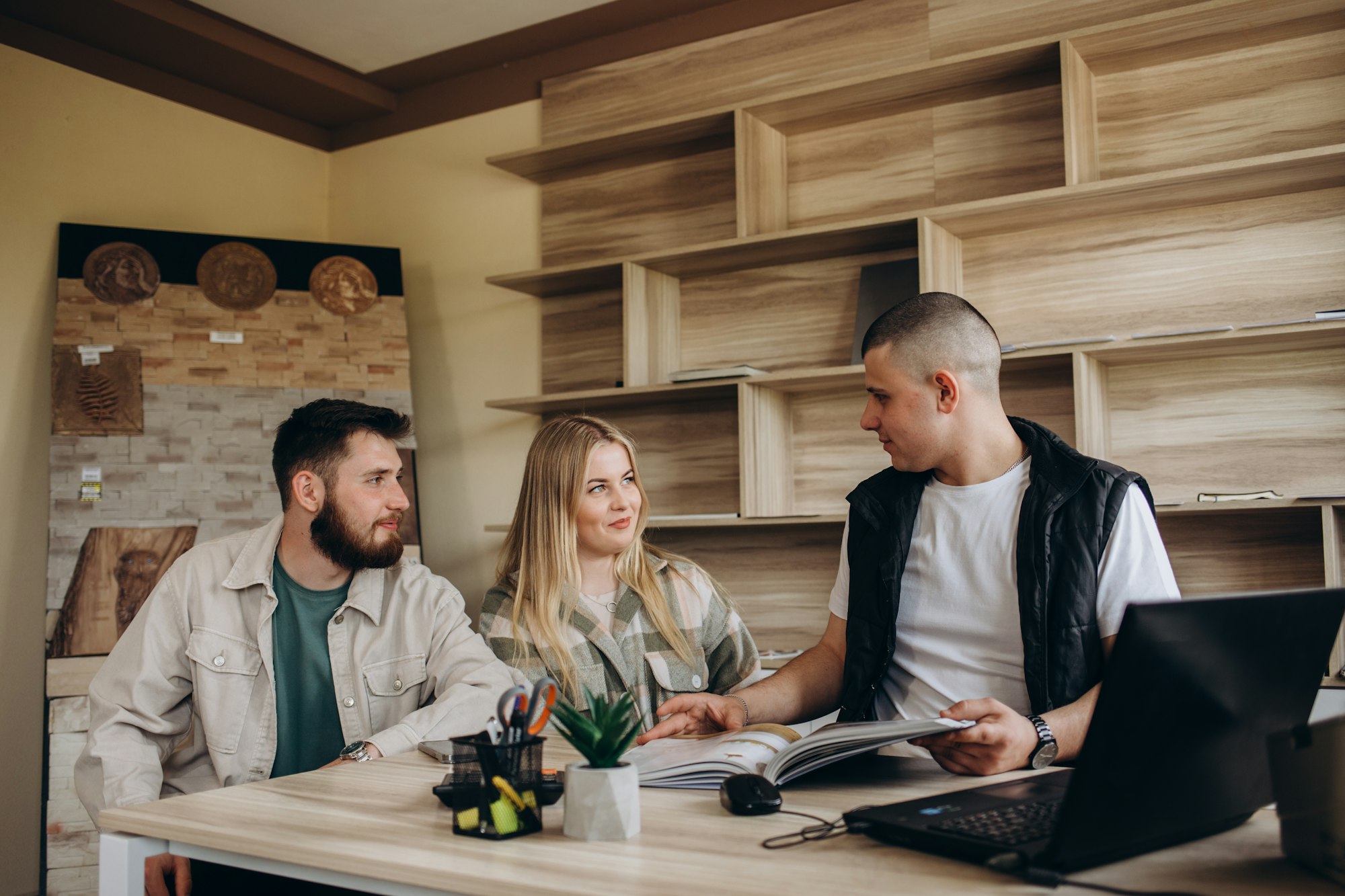 Competent seller consulting young couple about purchase of laminate flooring in store